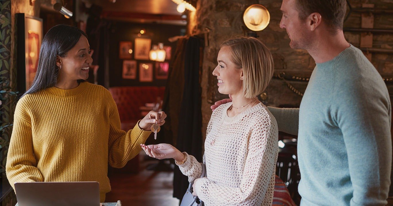 Photograph of receptionist at small hotel or b&b checking in a couple