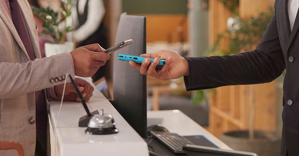 Guest paying securely at hotel reception desk with card and mobile terminal