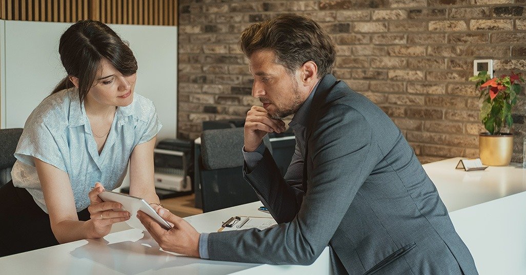 Photograph showing receptionist showing a guest hotel booking details on a tablet at the front desk