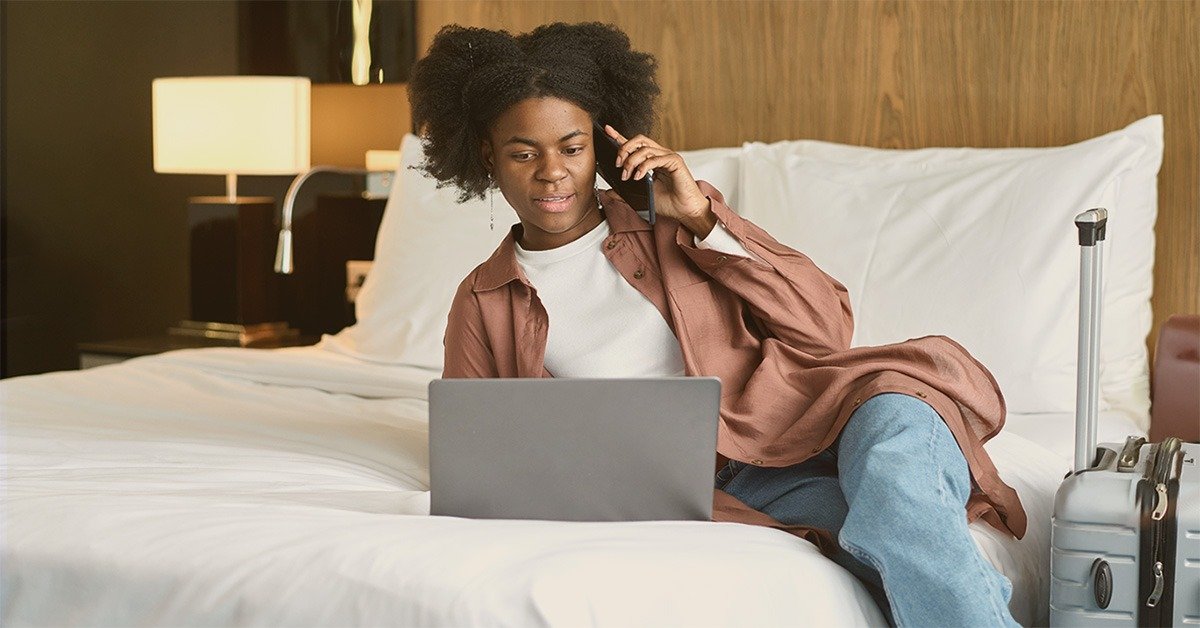 Guest booking on laptop while speaking on mobile phone, symbolizing the need for hotels and bed-and-breakfasts to diversify their booking channels.